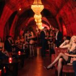 Coppie in lingerie e abito scuro in un club privé dalle volte di velluto rosso, d'inverno