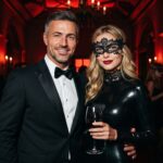 Coppia elegante in maschera a una festa Eyes Wide Shut, lei in latex nero